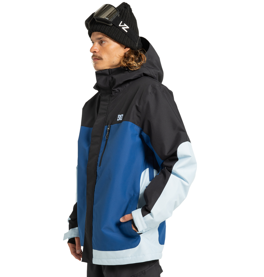 A man in a black beanie and goggles wears the DC Shoes Men’s Defiant Insulated Jacket in black, blue, and light blue. Crafted from recycled polyester with durable Weather Defense 10 technology, he faces left against a plain white background, confidently showcasing this winter essential.