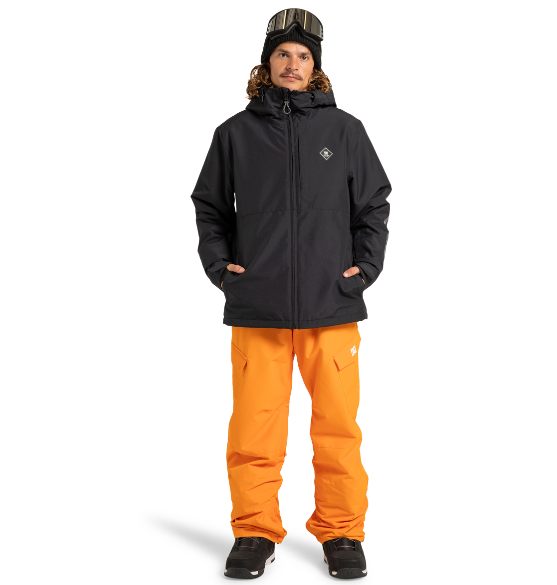A person wearing the DC Shoes Unisex Basis Insulated Jacket, orange snow pants, black boots, a black beanie, and ski goggles stands facing forward against a plain white background.