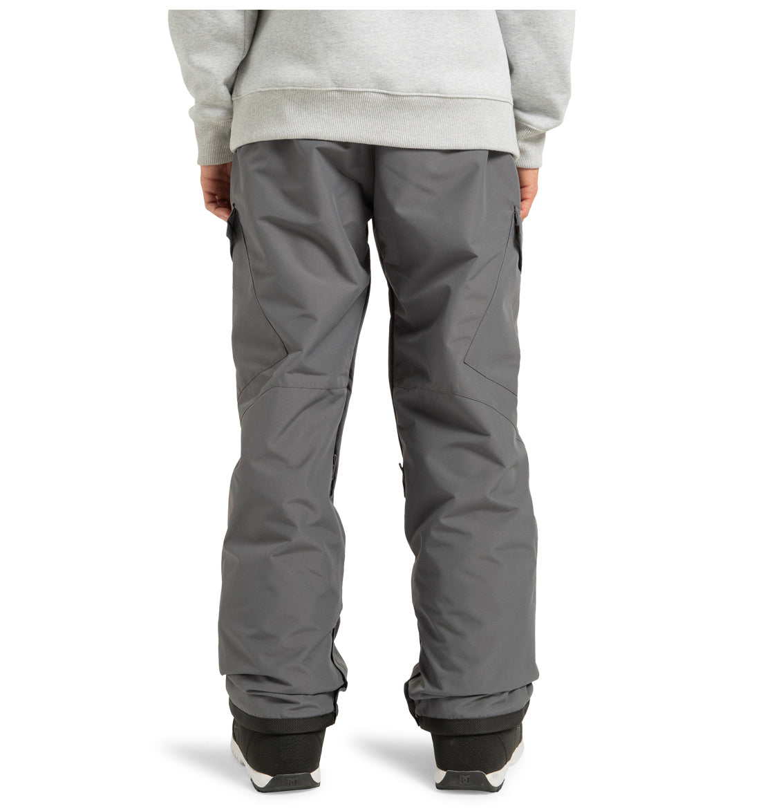 A person seen from the back is wearing gray, loose-fitting DC Shoes Men’s Banshee Insulated Pants made from recycled polyester, black shoes, and a light gray sweatshirt. The pants appear to be designed for winter mountain wear or snow activities.