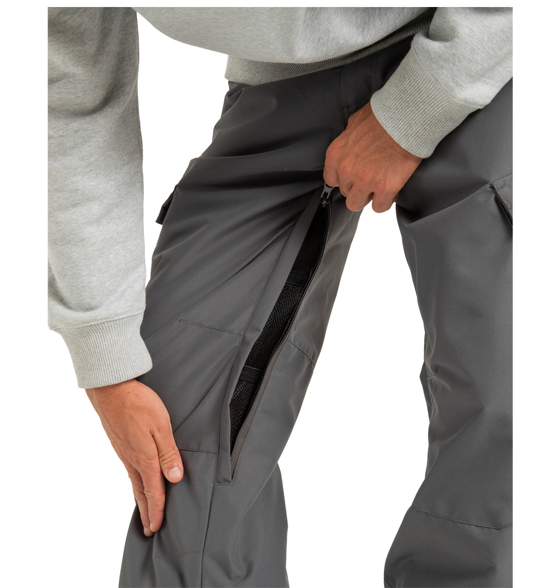 A person in a gray sweatshirt unzips the side vent of the DC Shoes Men’s Banshee Insulated Pants, revealing black mesh fabric underneath—showcasing the ideal winter mountain wear made from recycled polyester.
