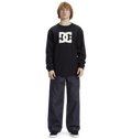 Young person with curly hair wears a black Men's DC Star Tee by DC Shoes, featuring bold graphics, paired with loose dark jeans and black sneakers, standing against a white background—ready to skate.