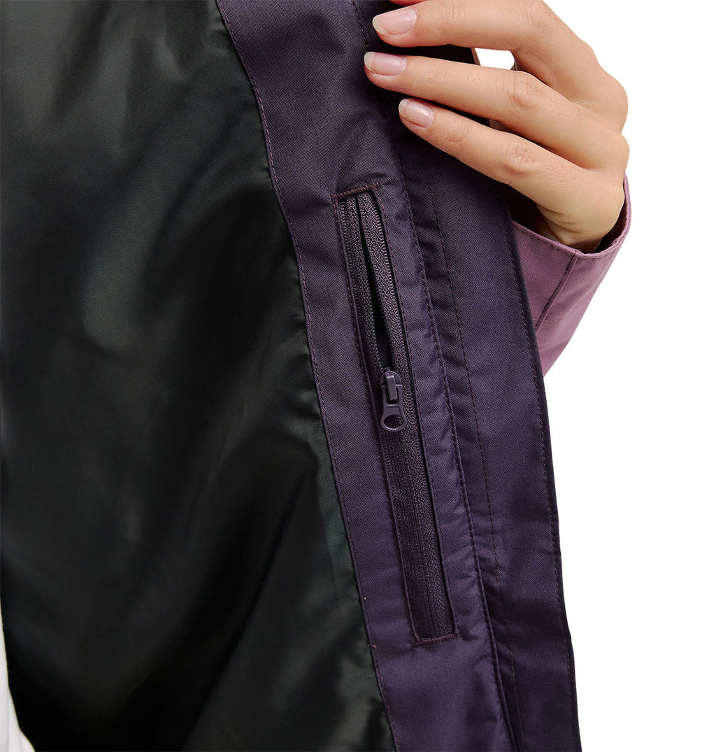 A hand holds open the DC Shoes Everfrost Jacket in purple, revealing its black inner lining and a small zippered pocket inside.