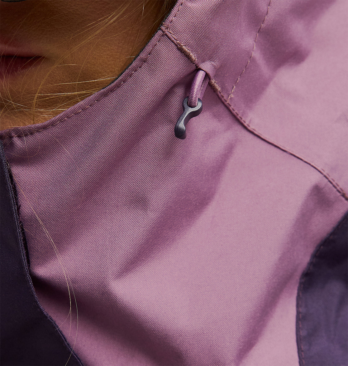 Close-up of the mauve-colored Everfrost Jacket by DC Shoes, featuring an insulated design with a drawstring and toggle, partially revealing the wearer’s face and hair.