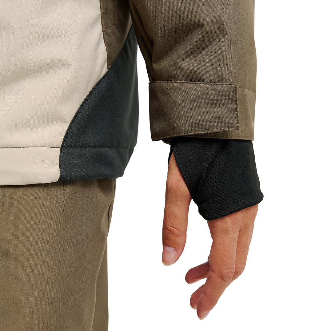 A close-up of a person wearing the DC Shoes Everfrost Jacket in tan and brown, featuring a black thumbhole sleeve that partially covers their hand.