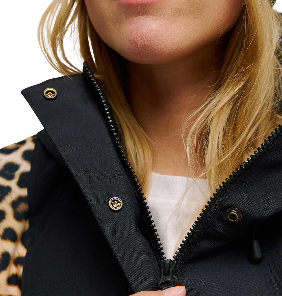 A close-up of a woman’s lower face and neck, wearing the DC Shoes Chalet Anorak with the zipper partially open, revealing a white shirt and a leopard-print sleeve.