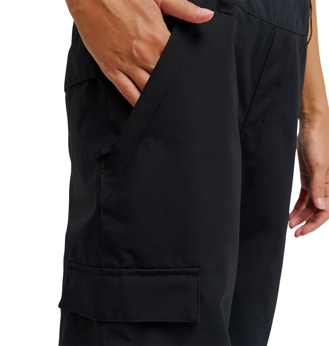 A person wearing DC Shoes Valiant Bib Pants, designed for breathable protection, places their left hand in the front pocket. The pants feature a side pocket with a flap. Only the lower torso and upper legs are visible.