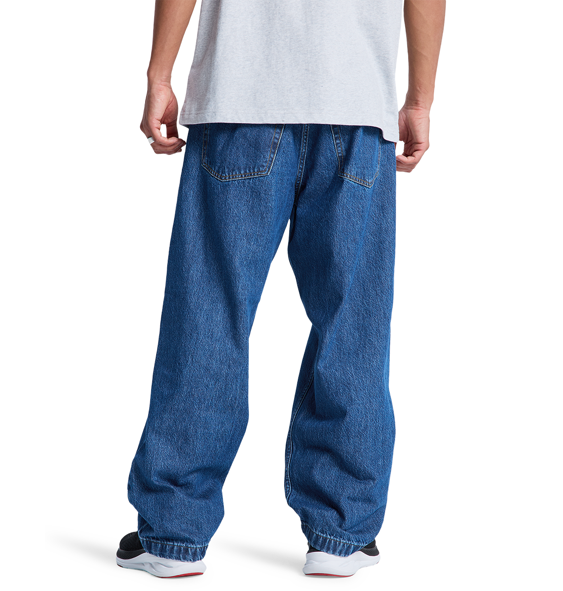 A person wearing a white t-shirt, DC Shoes Men's Baggy Denim Pant, and black and white sneakers stands with their back to the camera against a plain white background.