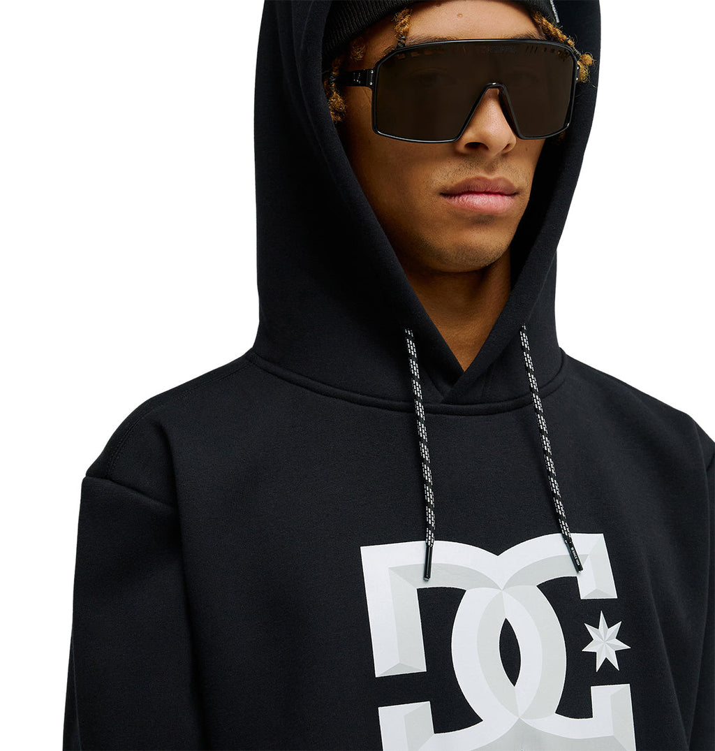 A person wearing the DC Shoes Snowstar black hoodie featuring a white DC logo, paired with large dark sunglasses and a black beanie—delivering reliable snow-day performance and a comfortable fit. The image is cropped at the shoulders and mouth.