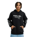 A person wearing the Men's Side Flame Hoodie from DC Shoes—a black pullover featuring bold white DC graphics on the front and sleeves—stands with hands in the spacious front pocket against a simple, light backdrop. The hoodie’s fleece construction delivers cozy warmth and stylish comfort to the overall look.