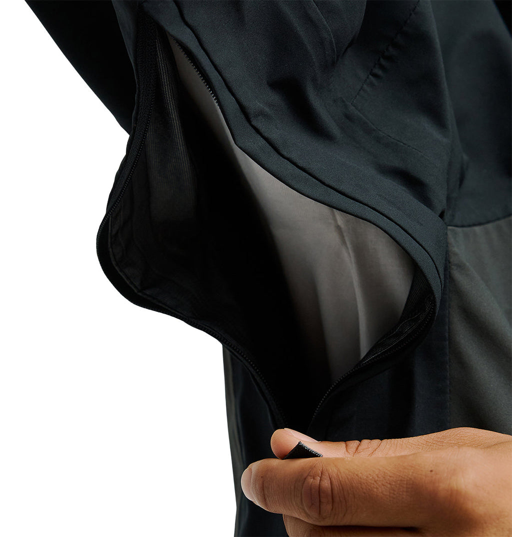 A close-up of a hand holding open the Storm Divison 3L Jacket 30K by DC Shoes, revealing its interior lining and zipper engineered for breathable protection.