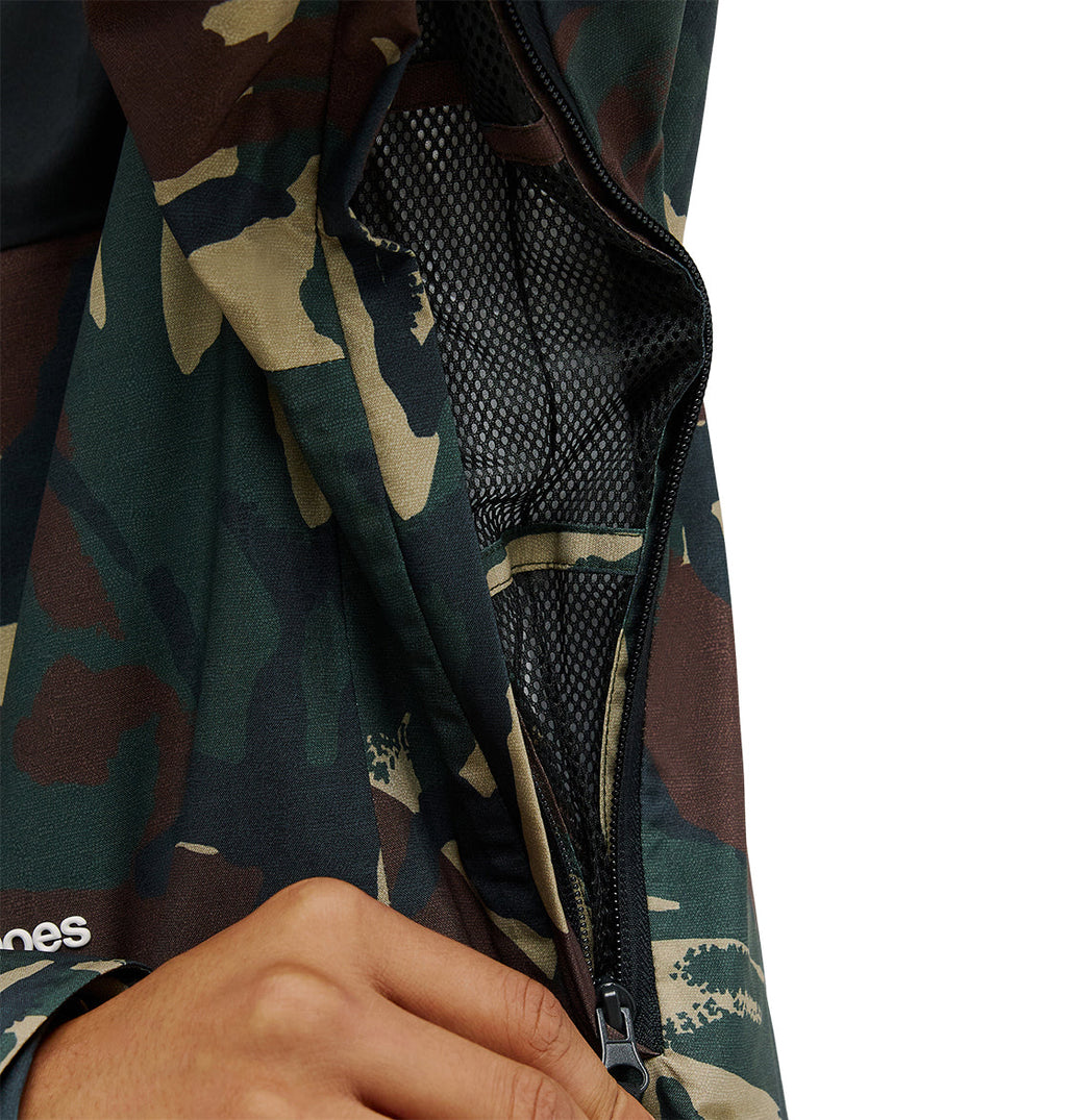 A hand pulls down the zipper of the DC Shoes Edge Jacket 20K, showcasing its camouflage-patterned waterproof exterior and a breathable mesh lining inside. The background is plain white.