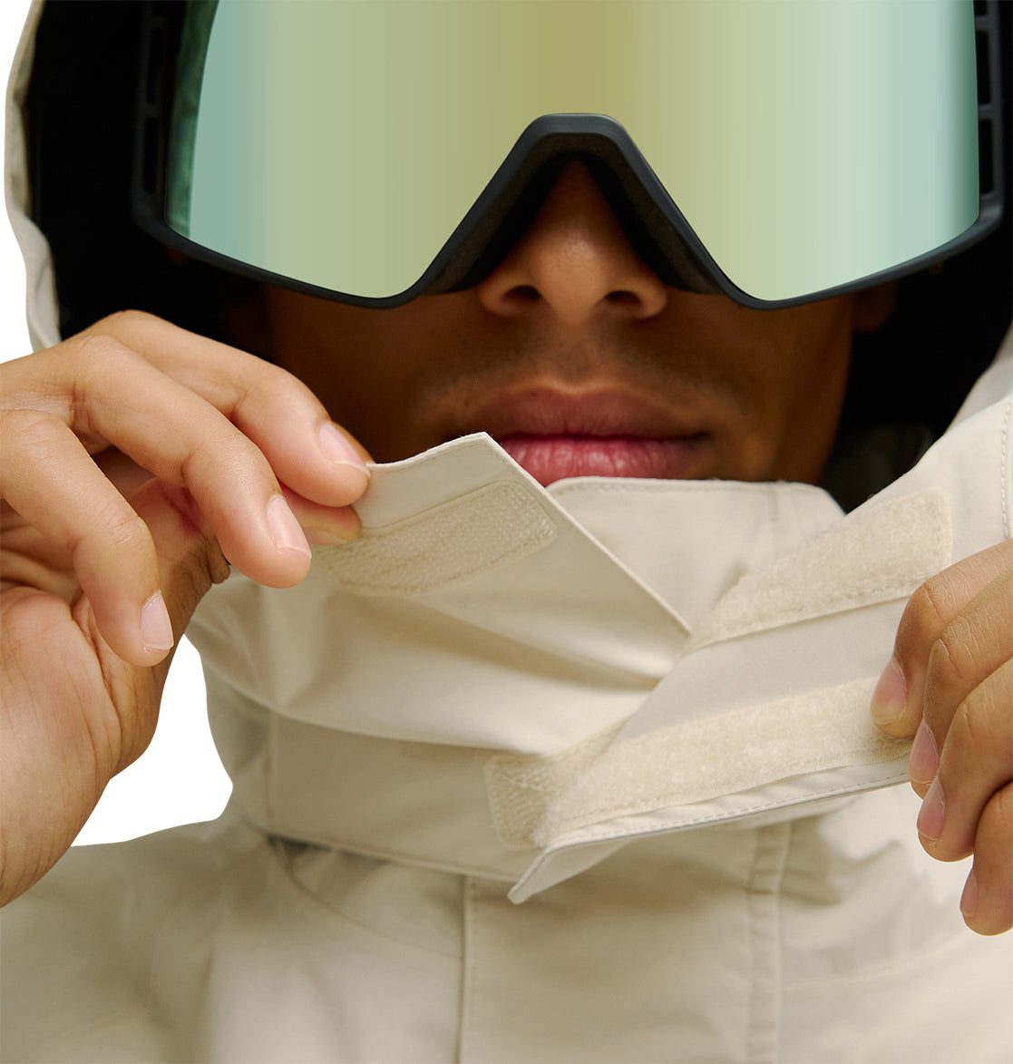 Wearing large reflective ski goggles, a person fastens the Velcro collar of the DC Shoes Mountain Lab Jacket 20K, highlighting its snow performance with only their lower face visible.