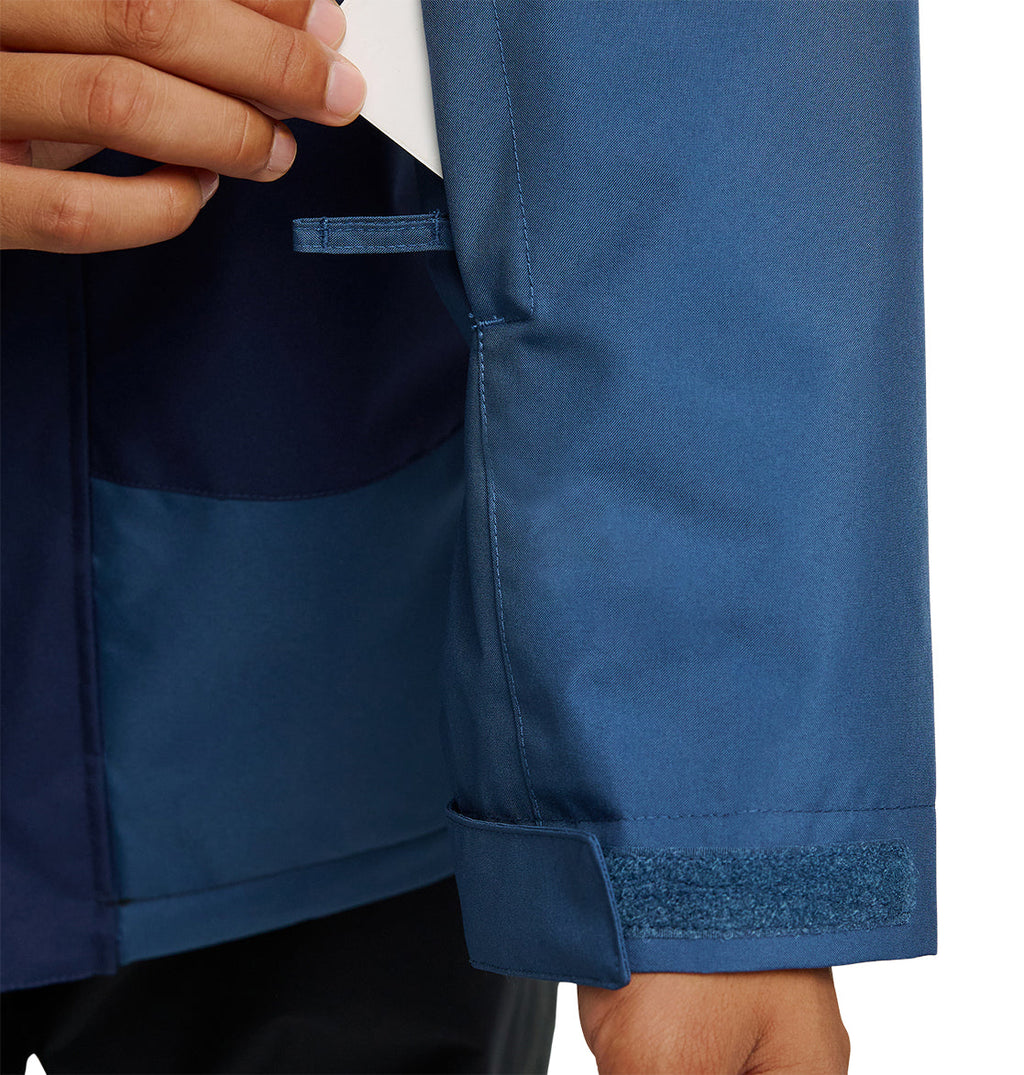 A person adjusts the Velcro cuff of a blue DC Shoes Coldsmoke Jacket 10K sleeve while holding a white object in their other hand, ensuring optimal waterproofing and breathable protection for enhanced comfort in challenging conditions.