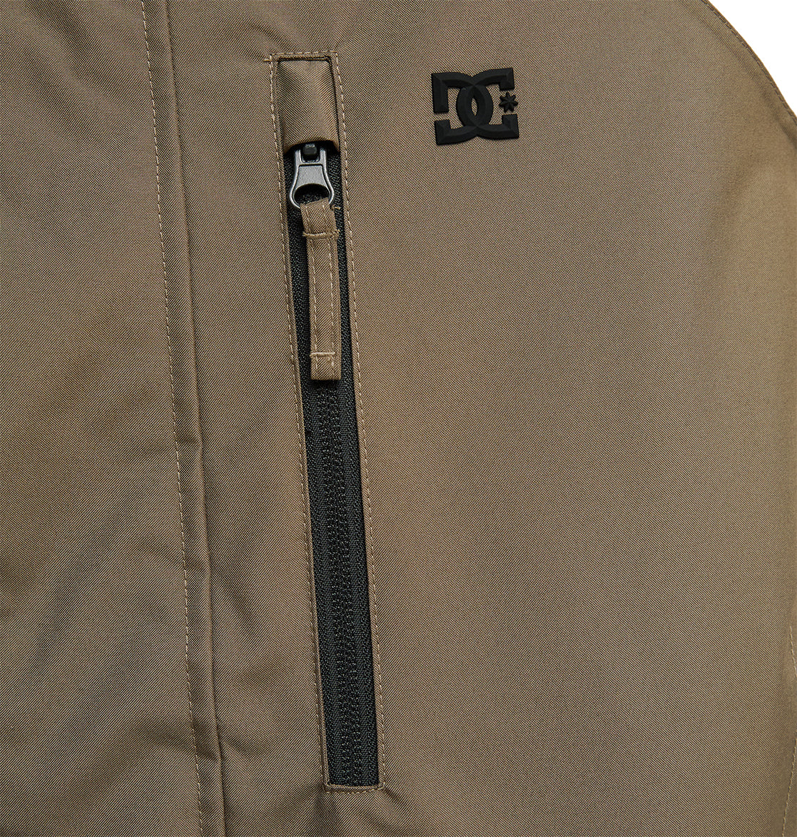 Close-up of the DC Shoes Coldsmoke Jacket 10K in brown, highlighting a vertical zippered pocket and a small black DC Shoes logo above the pocket; engineered for snow performance with breathable protection.