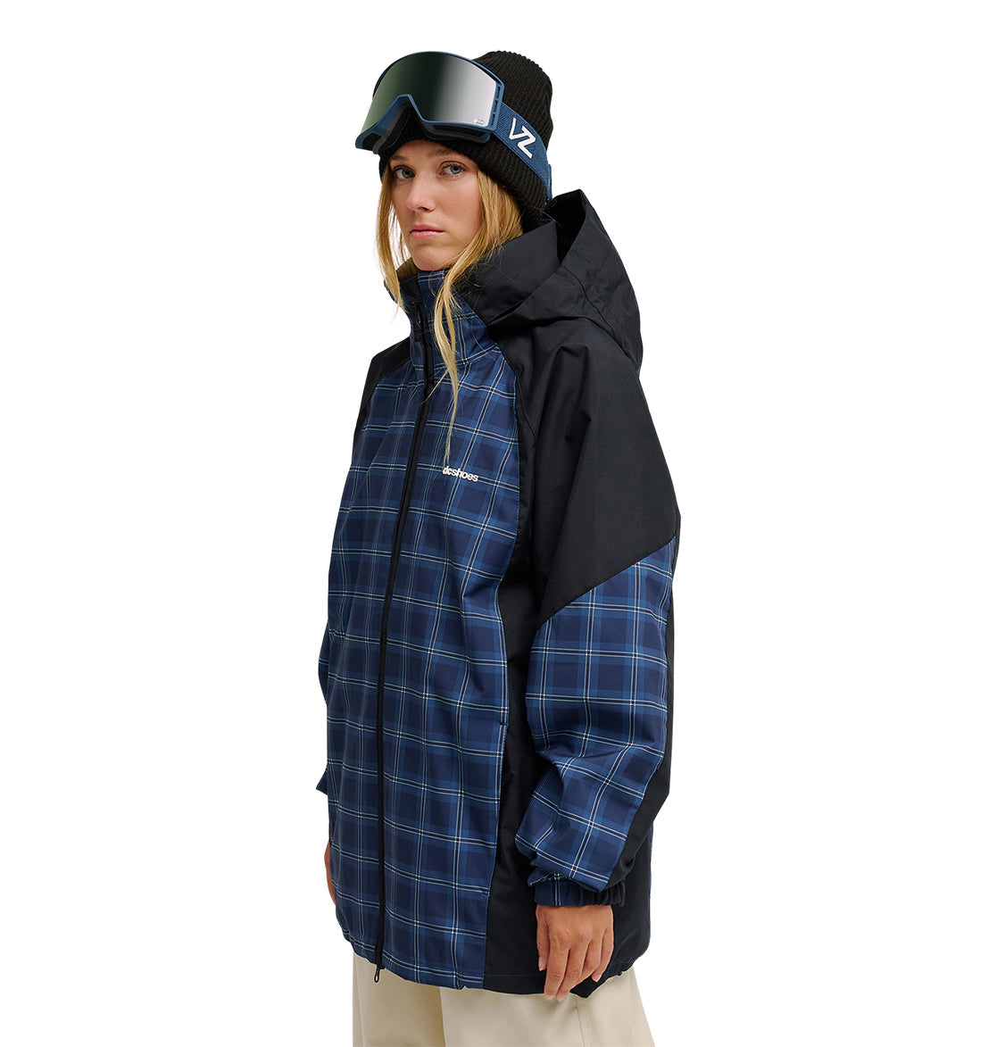 A person wearing the DC Shoes Trackstar Jacket 10K—a blue plaid winter jacket that offers breathable protection and superior waterproofing—along with a black beanie and ski goggles, stands facing slightly sideways against a white background.