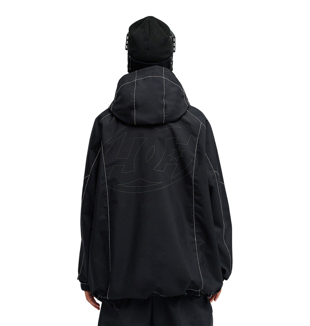 A person stands with their back to the camera, dressed in a loose black DC Shoes Trackstar Jacket 10K featuring prominent white stitching and a subtle oversized logo. Designed for snow performance, this jacket provides breathable protection ideal for cold weather. The individual also sports a black beanie.