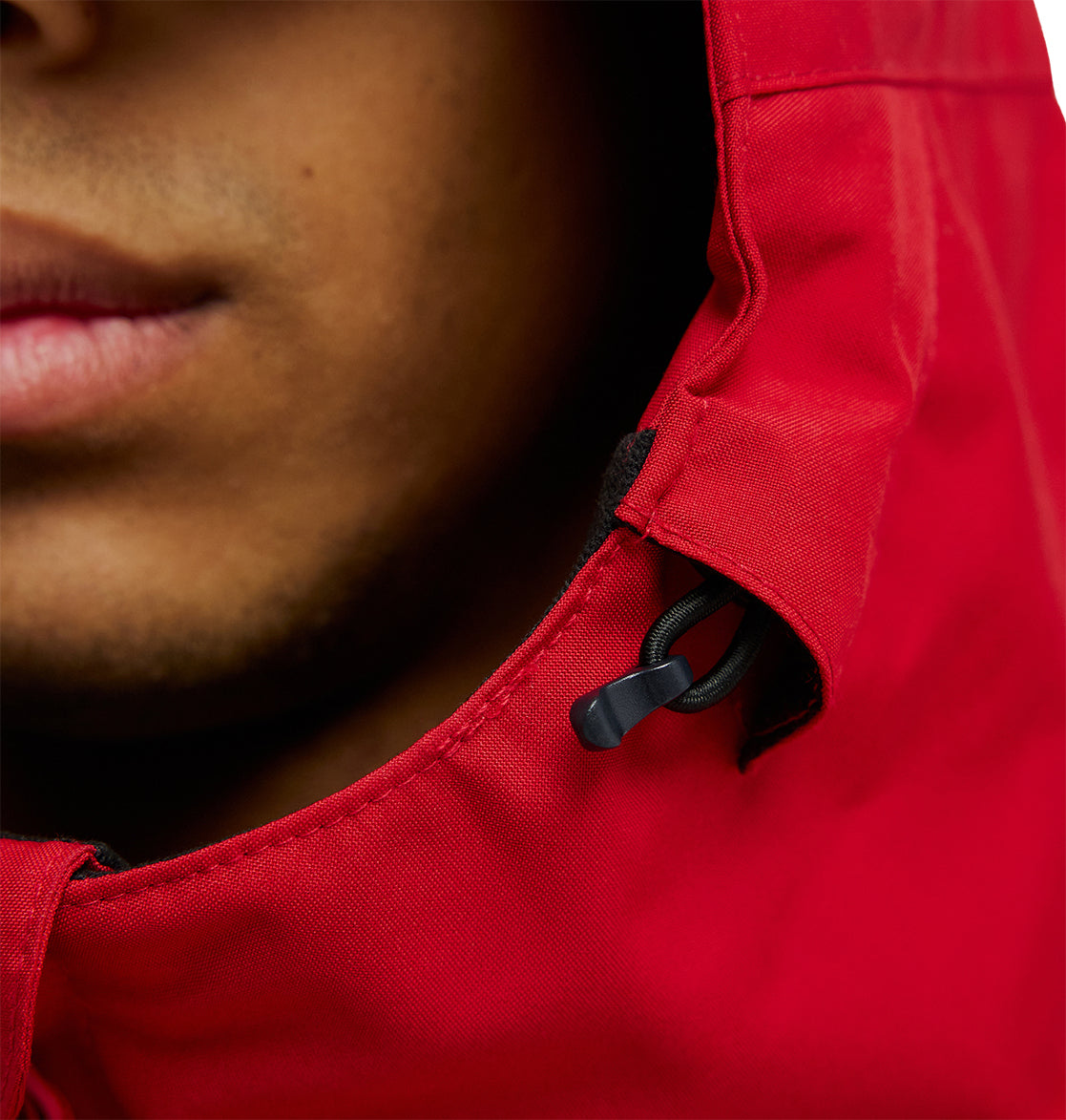 Close-up of a person’s lower face wearing the DC Shoes Basis Jacket 10K in bright red, with a black drawstring visible on the hood.