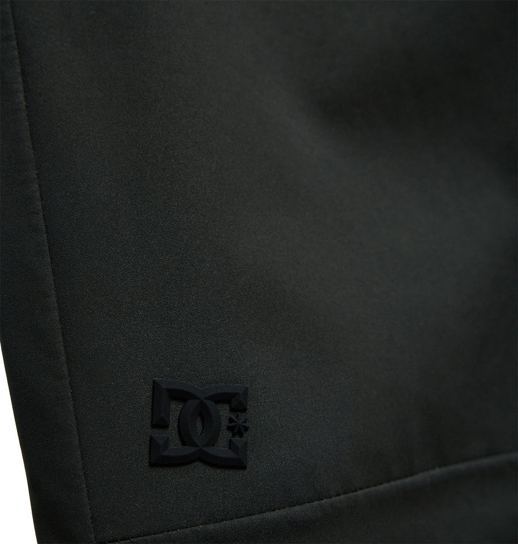 Close-up of the Storm Division 3L Bib 30K by DC Shoes, featuring black fabric with a subtle, embossed DC Shoes logo in the lower left corner. The smooth texture and visible stitching along the left edge showcase its breathable protection—perfect for all-weather comfort and performance.