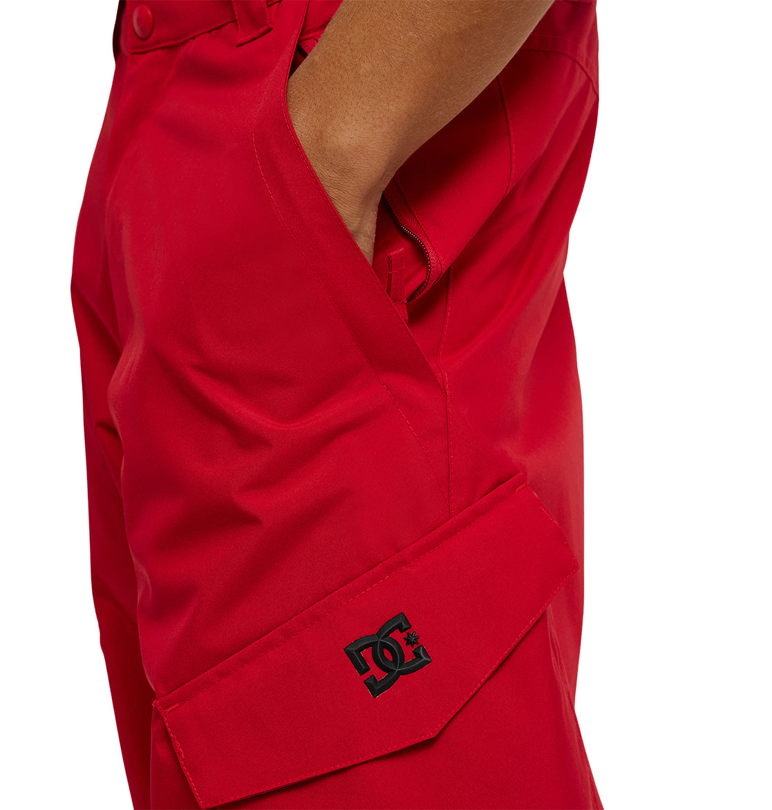 A person wearing bright red DC Shoes Banshee Pants with a hand in the pocket; the DC Shoes logo appears on a flap near the thigh.