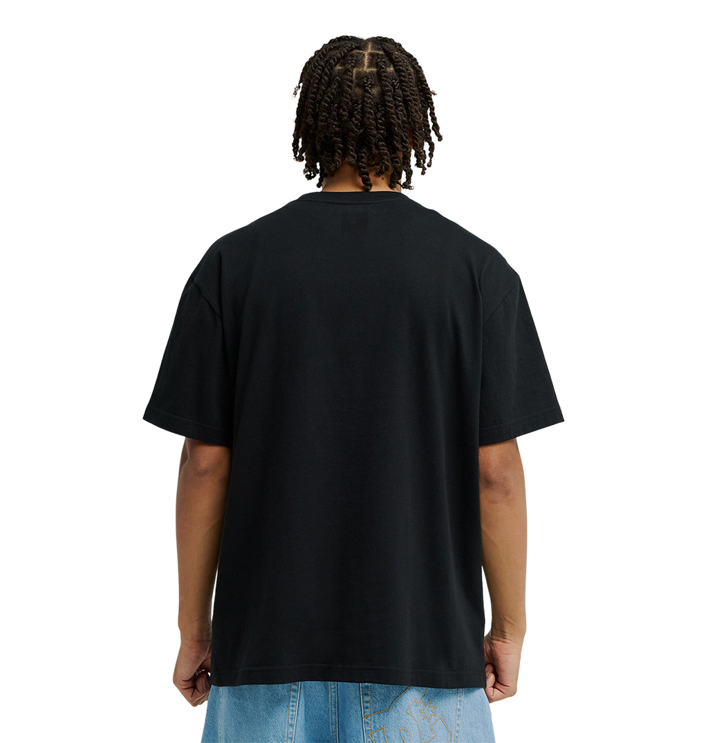 A person with short twists is shown from the back, wearing the Men’s DC Strass Star Tee by DC Shoes in soft cotton, paired with light blue jeans against a white background.