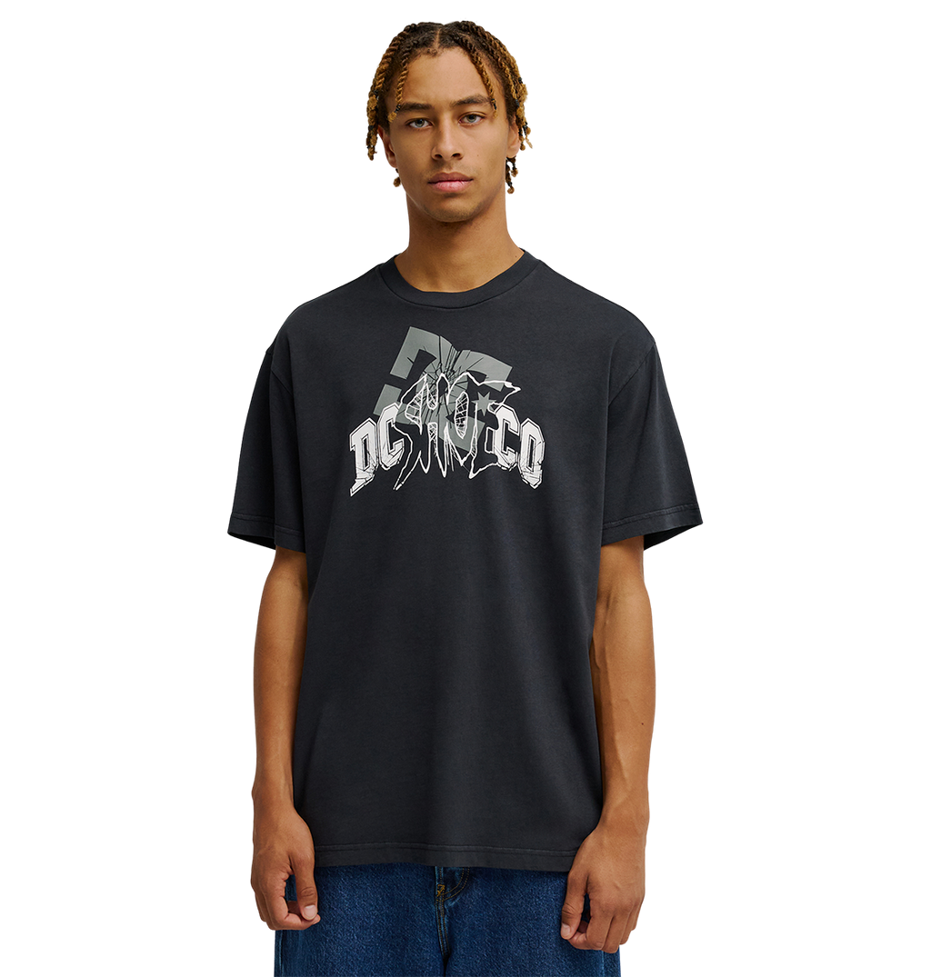 A person with braided hair wears the Men's DC Speratic Tee by DC Shoes—a relaxed fit black graphic skate t-shirt with a bold white logo—paired with blue jeans, standing against a plain white background.